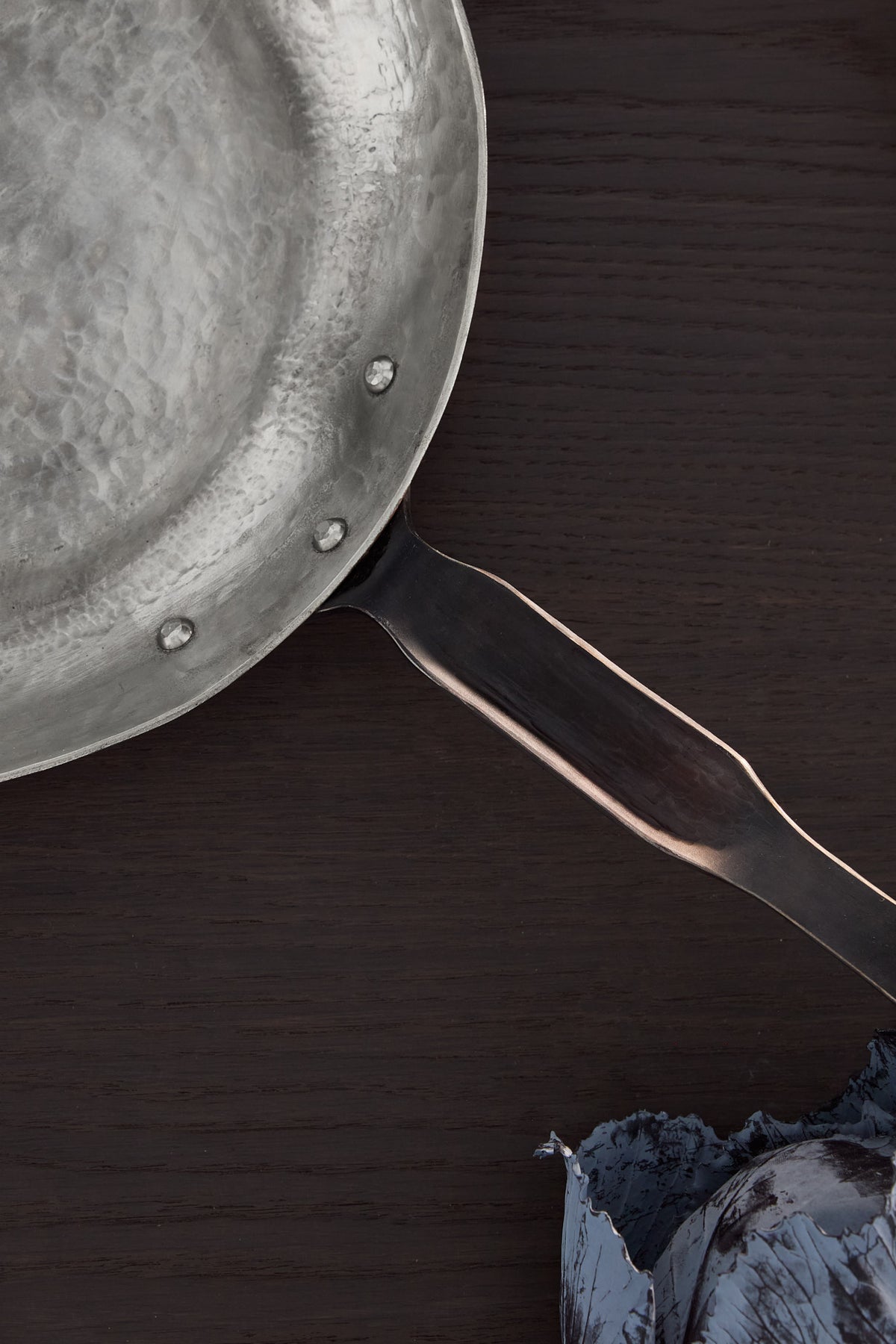 Interior view of hand raised copper pan with a focus on the handle